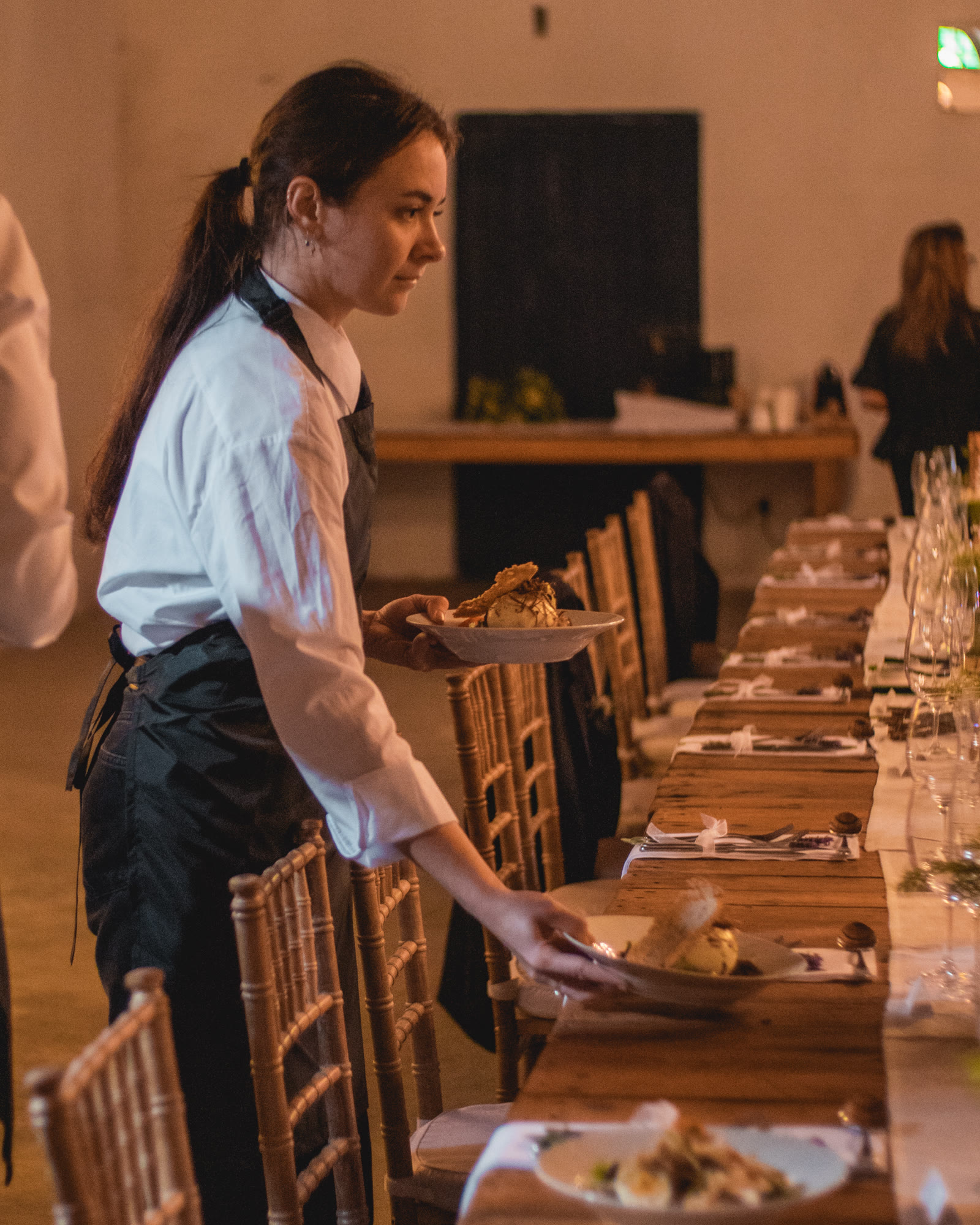 Waitron placing plates at a long wedding table