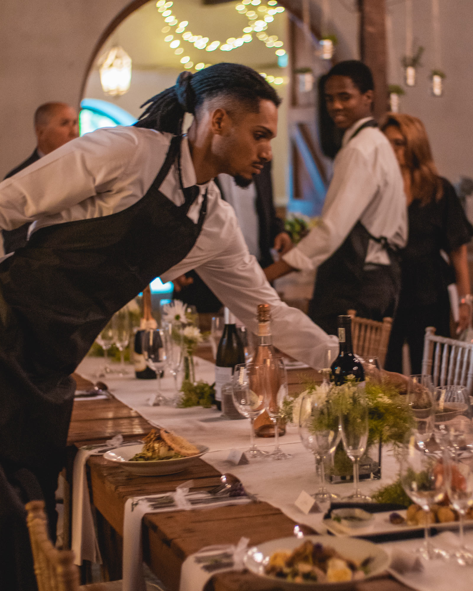Waitron setting glassware at an evening reception table