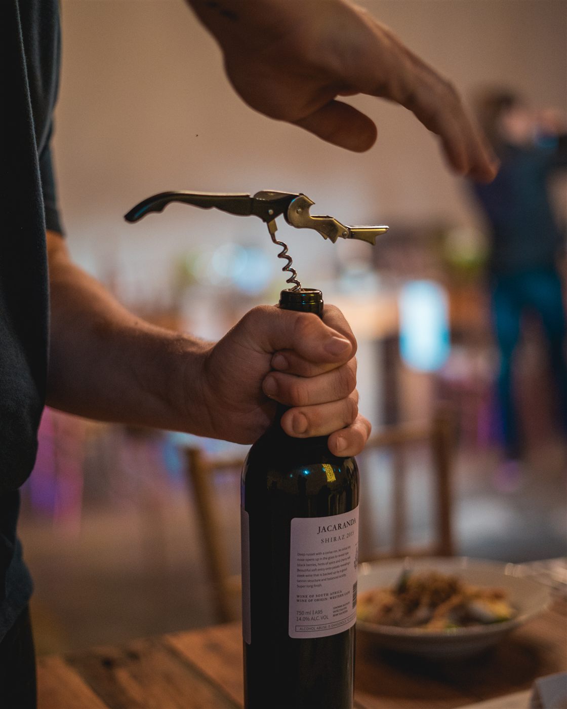 Hands opening a bottle of wine with a waiter corkscrew
